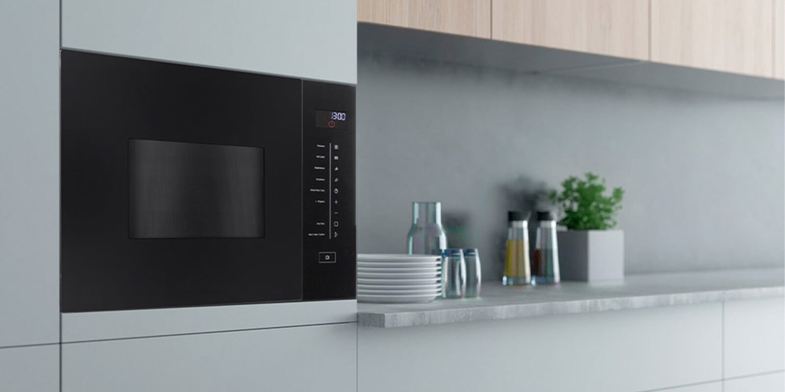 Moderne Einbau-Mikrowelle mit digitalem Display in weißer Küchenzeile, daneben Gläser, Teller und Gewürzbehälter